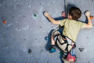 little boy climbing a rock wall indoor