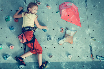 little girl climbing a rock wall indoor