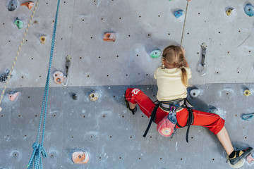 little girl climbing a rock wall indoor