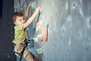 little boy climbing a rock wall indoor