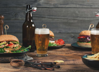 Different burgers, snack and lager beer on wooden table