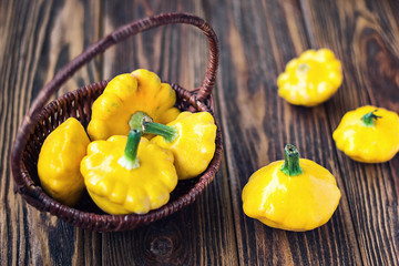 Yellow fresh pattypan squash in wooden basket on wood background. Delicious food. Selective focus.
