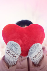 The woman in mittens holding a big red fluffy heart. for Valentine's day