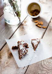 Morning light across raw cacao enery bars on white parchment paper with coconut and raw almonds on a wooden surface.