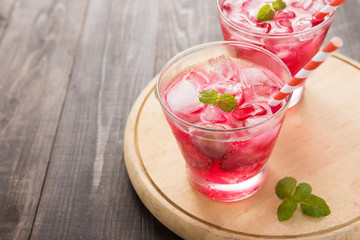 Red Cocktail with mint and ice on wooden table