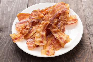 Closeup of fried bacon strips on white plate