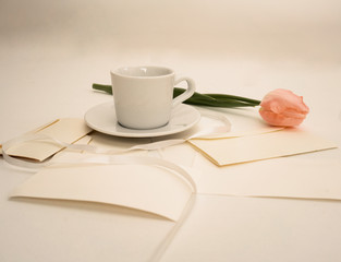 Pink tulip on a table with letters, envelopes and  cup of coffee