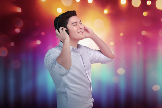 Cheerful asian man enjoying his favorite music in headphones