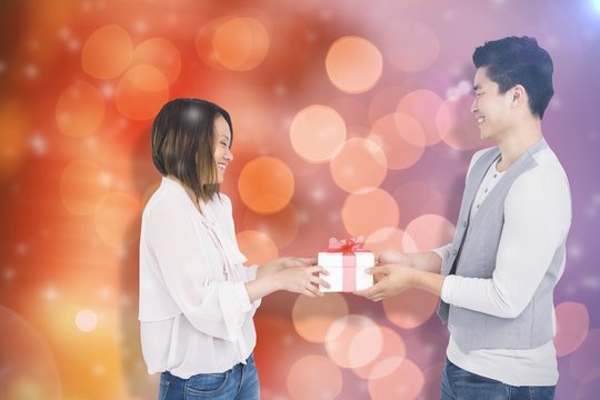 Composite image of young man giving present to woman