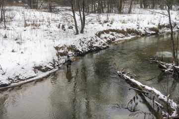 Fisherman with rod on a winter river. Tenkara fishing.