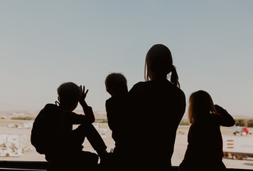 family travel- mother with three kids looking at planes in airport