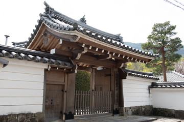 A beautiful and decorated gate of a temple can be seen in this picture. A tree can also be seen behind the gate.
