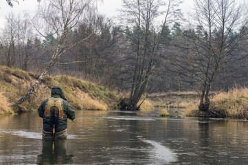 Fisherman fishing on a small spring river. Fly fishing.