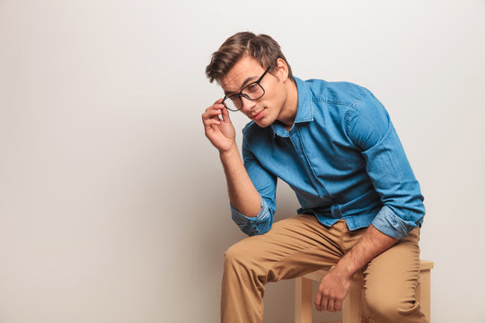 Young Casual Seated Man Is Taking Off His Glasses