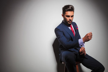 seated elegant man in suit is gesturing while looking down