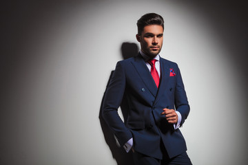 stilish man in double breasted suit standing against grey wall