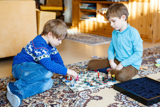 Two Little Kid Boys Playing Chess Game At Home.