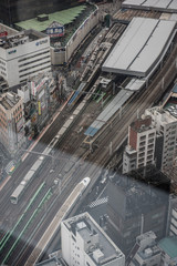 Fototapeta premium A birds eye view of a railway station where we can see two trains coming from a opposite direction in different tracks. Few high rise buildings can also be seen in the picture.