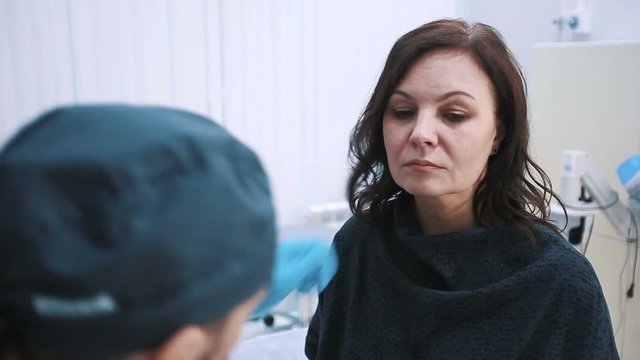 plastic surgeon checking middle aged woman face before cosmetic surgery