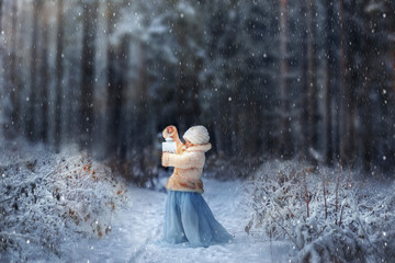 Winter fairytale. Little girl with lightning in frozen forest on Christmas eve