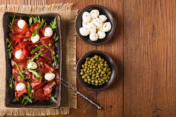 Beef carpaccio served with balls of mozzarella cheese, arugula a