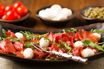 Beef carpaccio served with balls of mozzarella cheese, arugula a