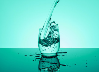 Bottle with creative splashing water in the glass