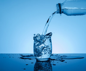 Bottle with creative splashing water in the glass