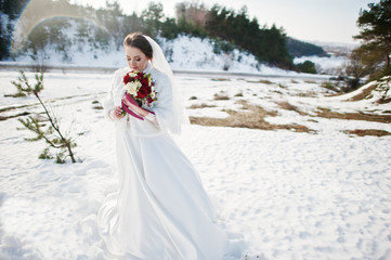 Fototapeta na wymiar Portrait of cute brunette bride with bouquet on hands at frost a