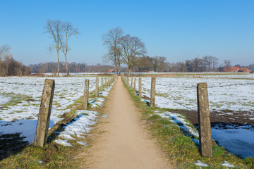 Sandpath between snowy meadows in dutch winter