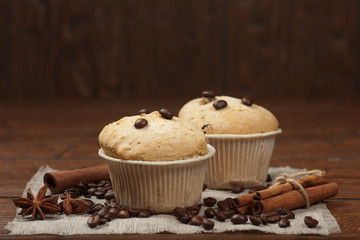 Tasty muffin cakes on burlap, spices and coffee beans