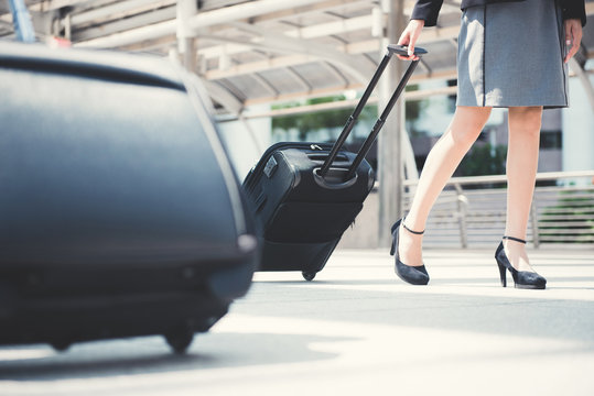 Businesswoman (lower part) walking and pulling luggage