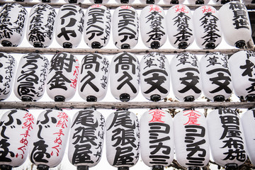 Fototapeta na wymiar Japanese decorations with japanese inscriptions written inside a buddhist temple. The white colored round shaped designs looks beautifully arranged in a row.