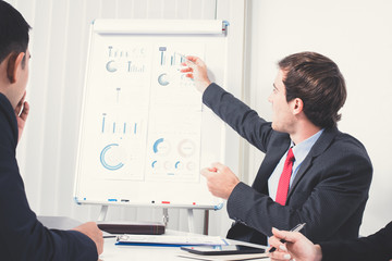 Young businessman as a meeting leader pointing on the graph