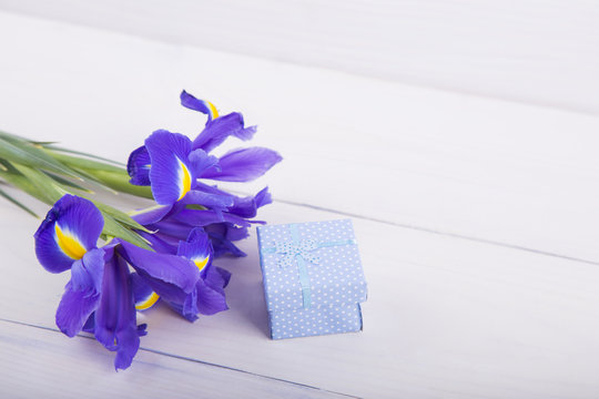 Bouquet of irises with gift box on white wooden background