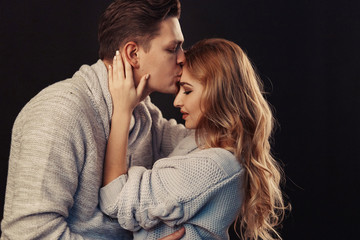 Cheerful couple in winter clothes hugging and kissing. Low light