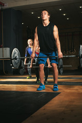 Three adults exercising with barbells in gym