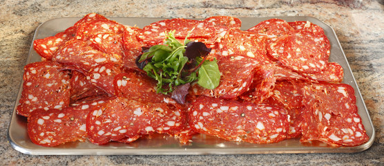 Platte mit Salami und Salat belegt