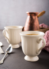 Two retro cups of coffee and old coffee pot on dark brown background with copy space.
