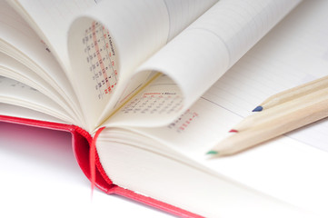 Date in red notebook, heart of pages and color pencils.