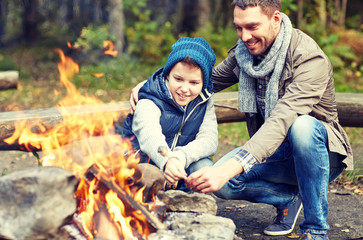 father and son roasting marshmallow over campfire