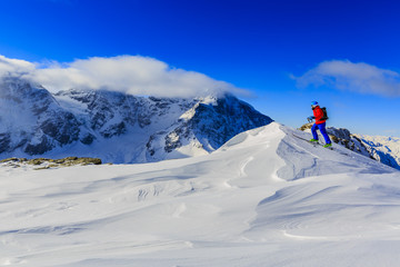 Naklejka na ściany i meble Mountaineer backcountry ski walking up along a snowy ridge with