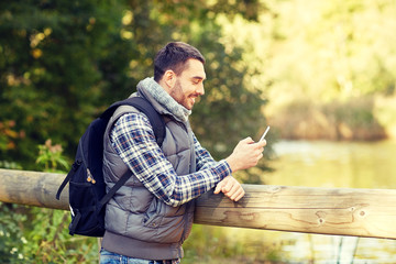 happy man with backpack and smartphone outdoors