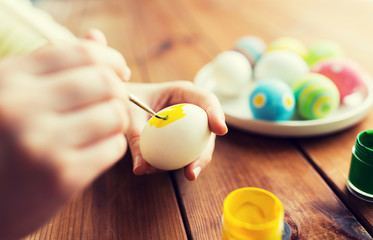 close up of woman hands coloring easter eggs