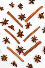 Composition made of star anise and cinnamon sticks isolated on white. Abstract pattern flat lay, top view, vertical.
