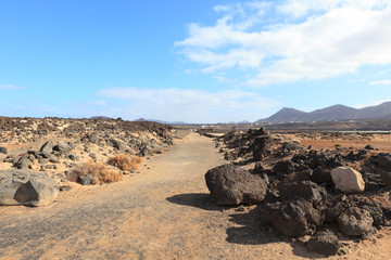Fototapeta na wymiar A road going through lava landscape in the Canary island of Lanzarote