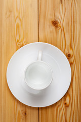 Empty ceramic cup with plate on a wooden table, top view, vertical