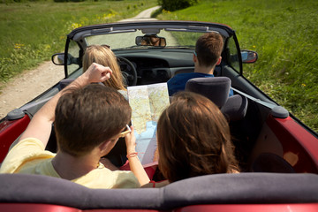 happy friends with map driving in convertible car