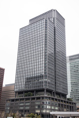 In the picture we can see a modern high rise building in focus. At the background we can see few other high raise buildings. The building is made of glass and enhanced modern architecture