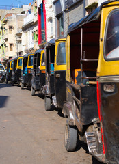 Yellow black rickshaws (tuk tuk) lined up in the street of Udaipur, Rajasthan, India.